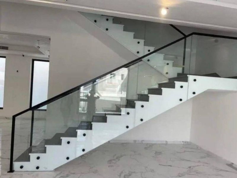 modern indoor glass staircase railing with black handrail and professional side mounting for luxury villas in riyadh.